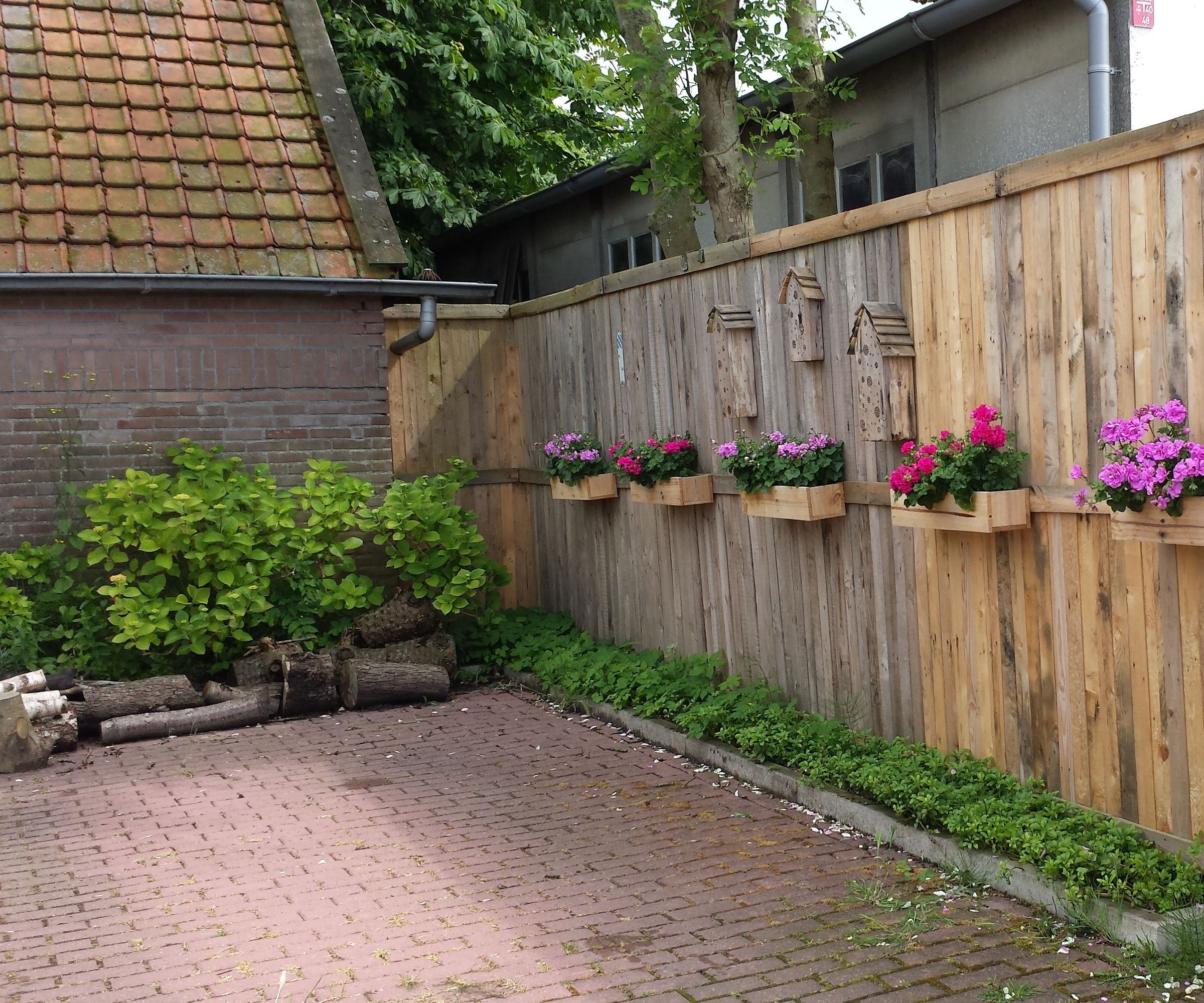 A Pallet Fence With Flower Boxes and Bee Hotels