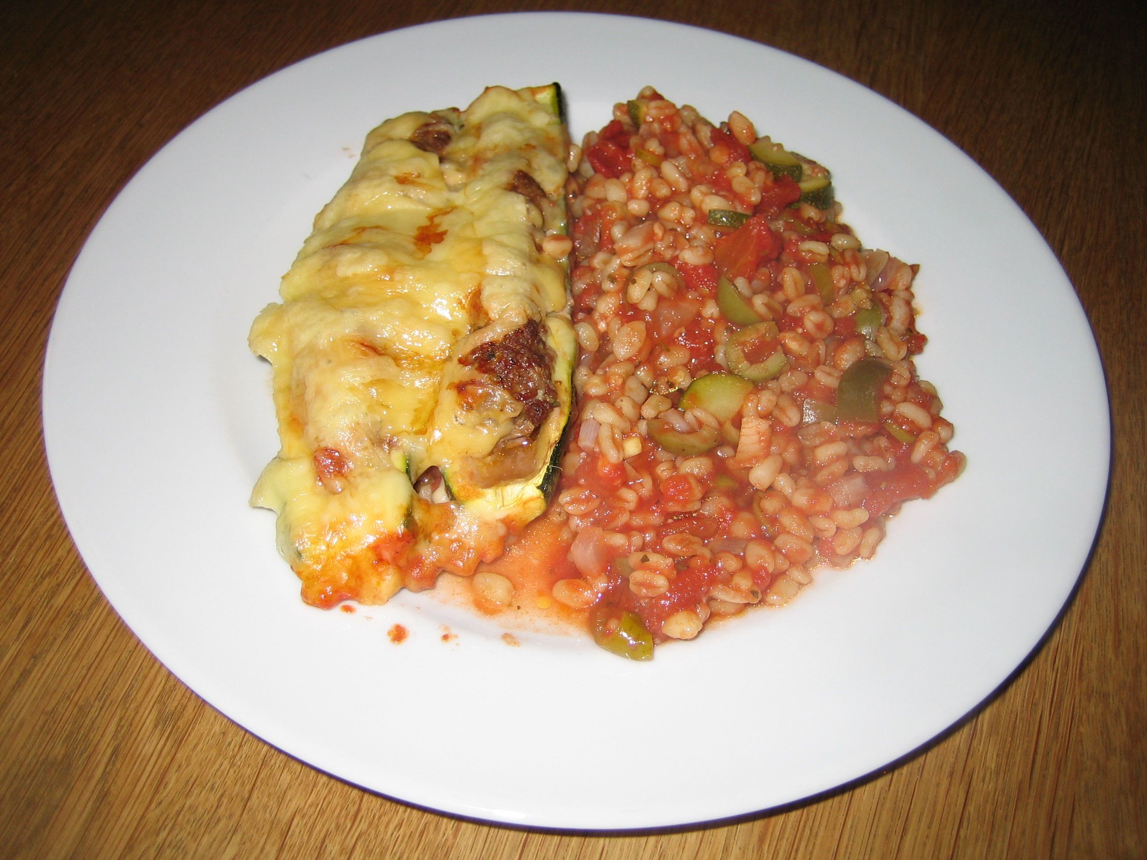 Filled Zucchini Halves on a Mediterran Tomato-wheat Bed