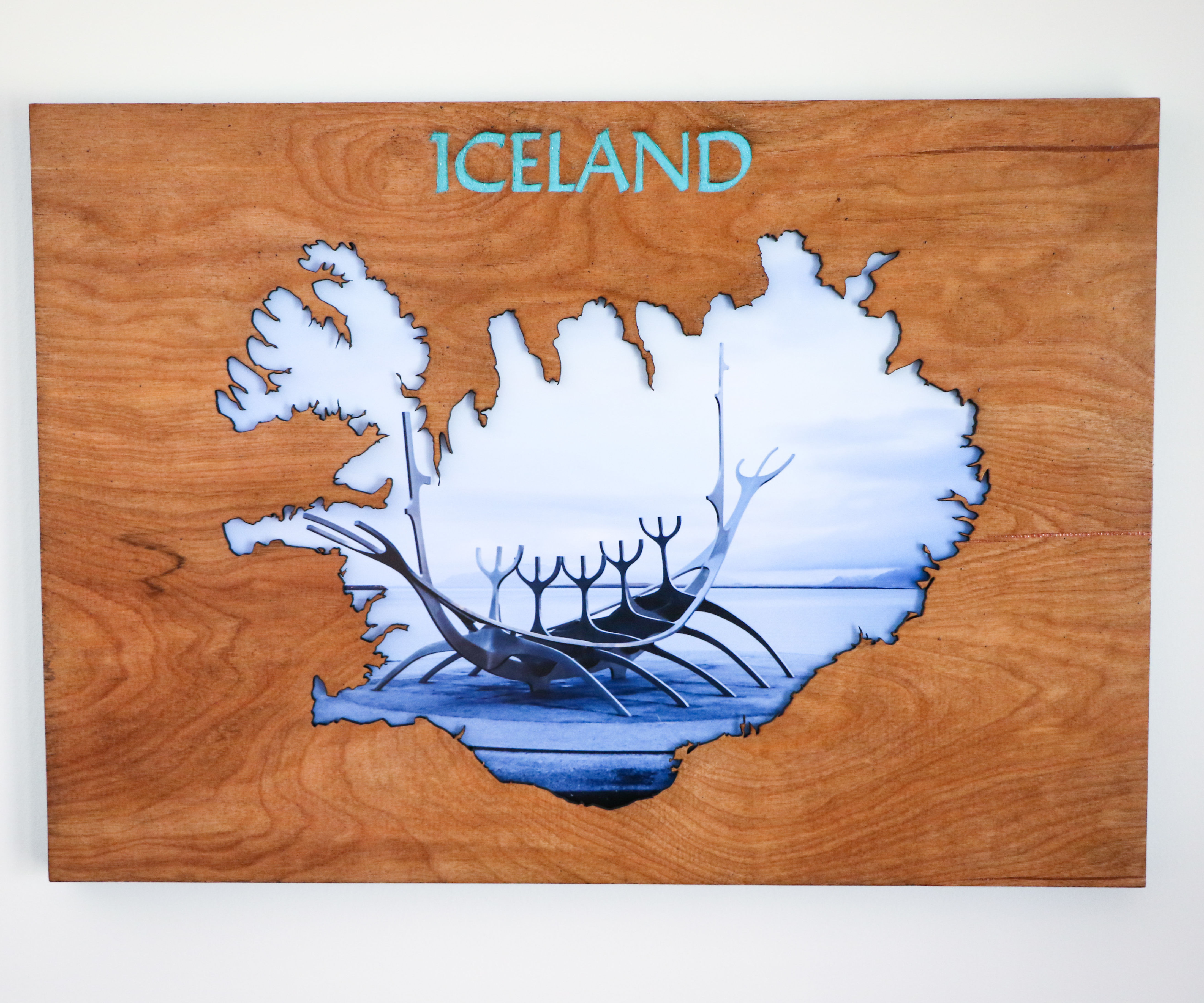 Wood Cutout of Iceland With Picture Behind It
