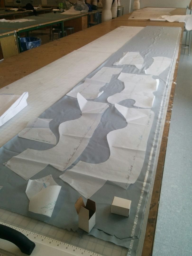 Paper garment pattern pieces arranged on fabric for cutting