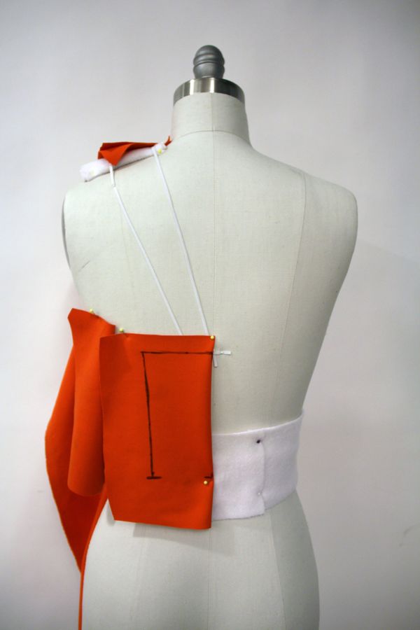 Sample-development reference: trial bodice fabric pinned on a dress form with marked construction lines.