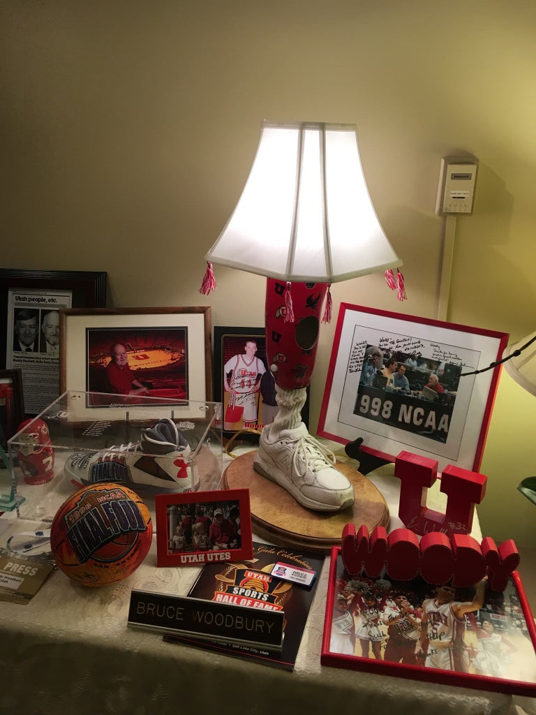 Prosthetic leg lamp on display on a table with lots of sports memorabilia from the University of Utah Prosthetic Leg Lamp at Funeral Viewing Table